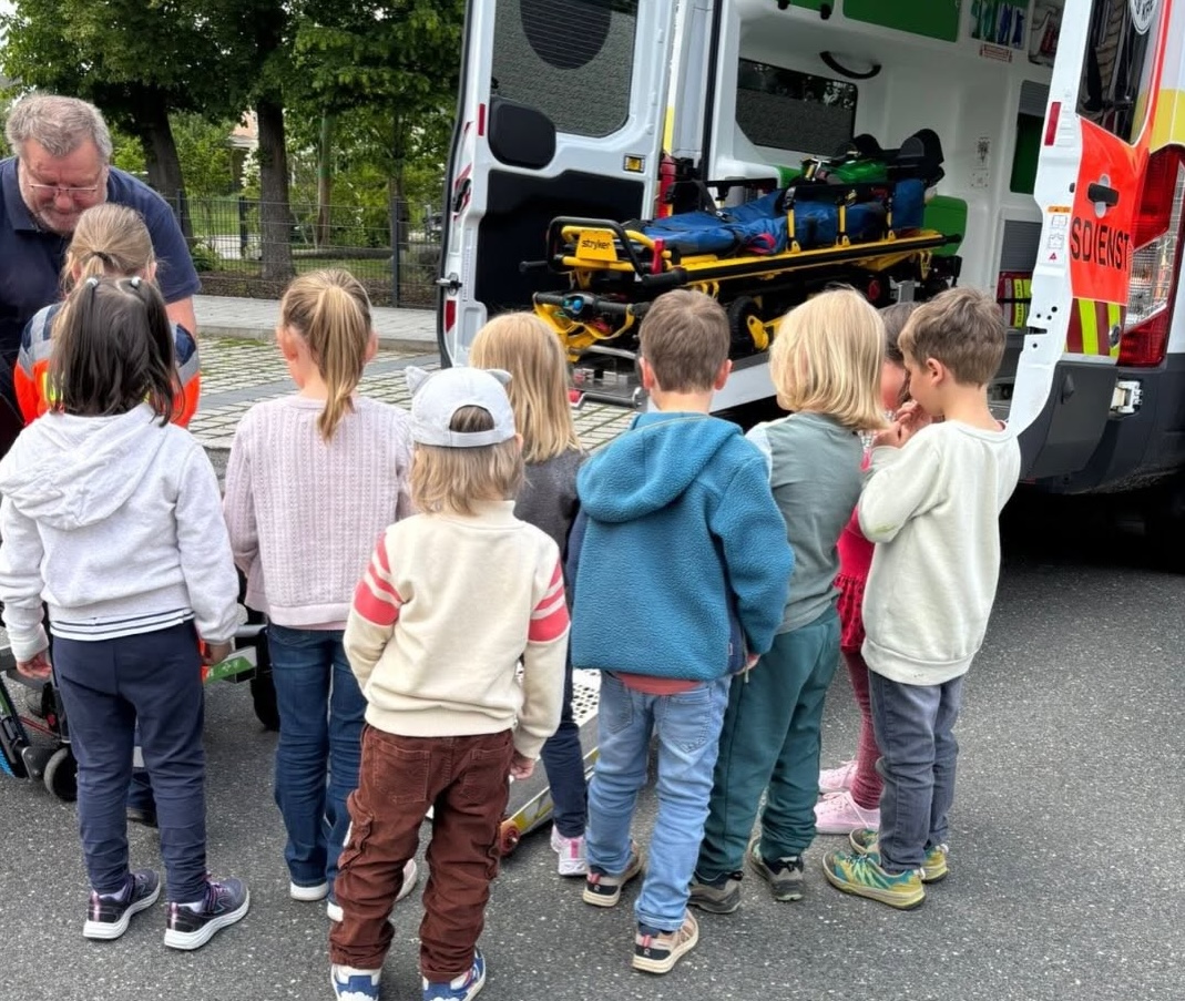 BRK-Team erklärt Kindern einen Krankentransportwagen
